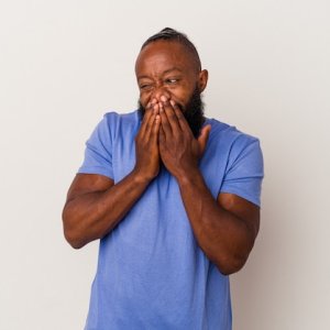 african-american-man-with-beard-isolated-pink-background-laughing-about-something-covering-mou...jpg